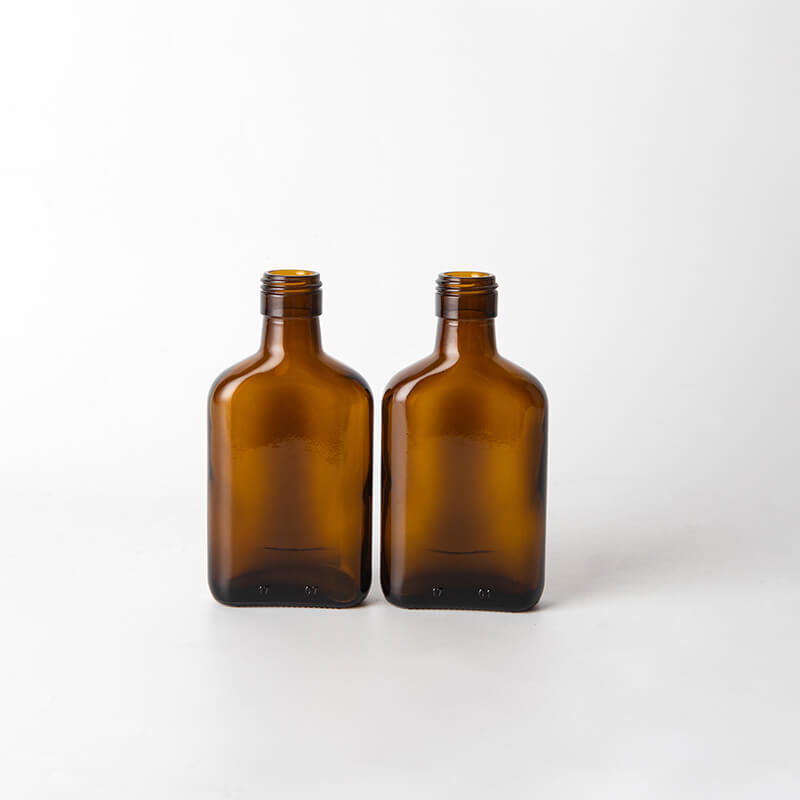 Flache bernsteinfarbene kleine alkoholische Glasflasche mit Schraubverschluss